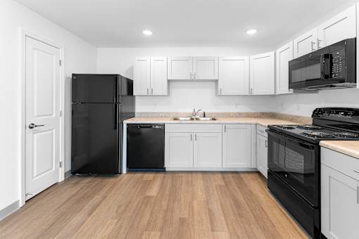 A kitchen with black appliances and white cabinets.at Union at North Crossing, Iowa