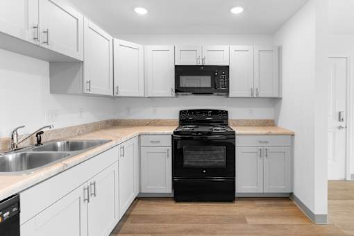 A black stove in a kitchen with white cabinets.at Union at North Crossing, Iowa, 50703