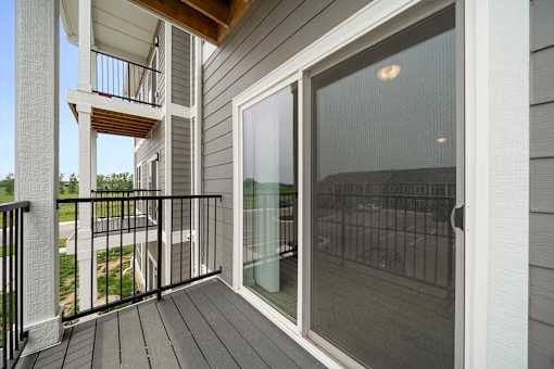A balcony with a glass door and a black railing. at Union at the Loop, Lawrence, KS, 66046