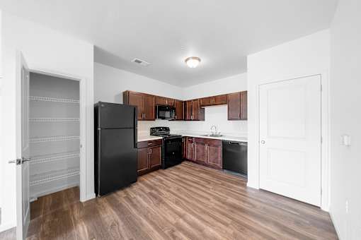 A kitchen with a black refrigerator and wooden cabinets. at Union at the Loop, Lawrence, Kansas
