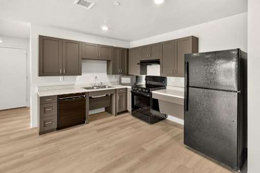 Modern kitchen with brown cabinets and black appliances at Union at Rivers Edge Apartments, Iowa, 50315