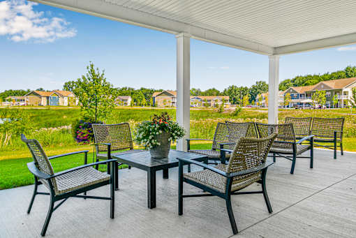 A patio with a table and chairs overlooking a residential area. at Union at Oak Grove, Howell, 48855