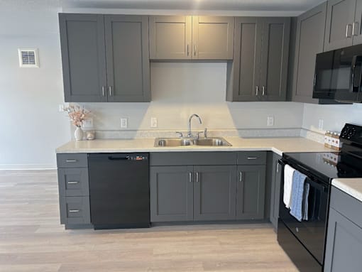 A kitchen with black cabinets and a black dishwasher at Union at Rivers Edge Apartments, Des Moines