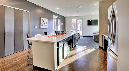 A kitchen with a white counter top and a fridge on the right.at Union at Crescent, Bloomington, 47404  