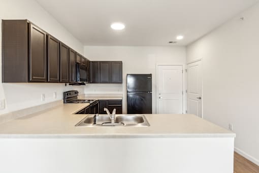 A kitchen with brown cabinets and a black fridge at Union at 16th, Indianapolis, IN