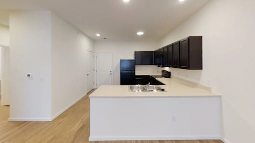 A modern kitchen with a white island and wooden floors.at Union at 16th, Indiana, 46222