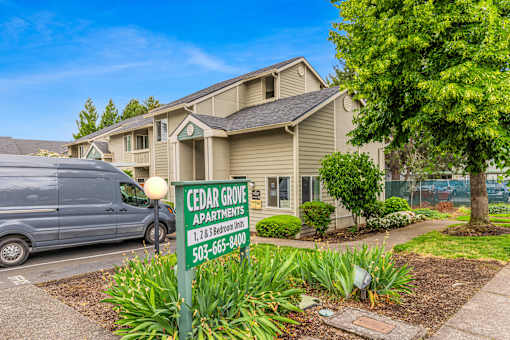 A sign for Cedar Grove Apartments is in front of a building.