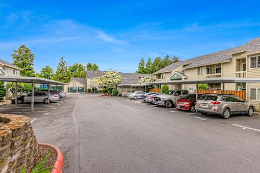 A parking lot with cars parked in front of apartment buildings.