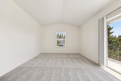A room with a carpeted floor and a window showing a view of trees.