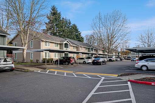 A parking lot with cars and apartment buildings in the background.