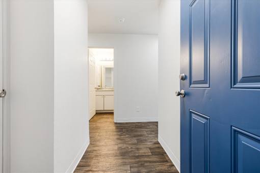 A long hallway with a blue door on the right.