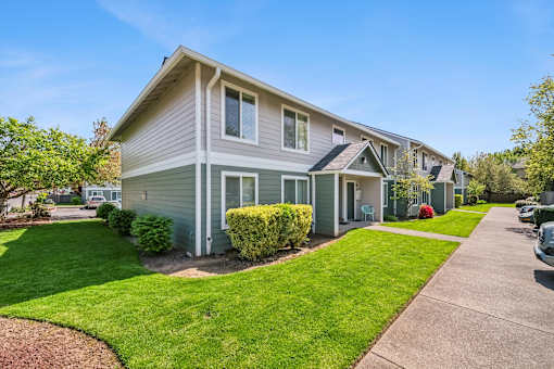 A grey house with a green lawn in front.