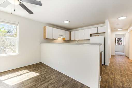 A spacious kitchen with white cabinets and a ceiling fan.