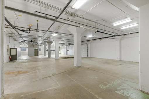 Oak Street Building A large, empty industrial space with a concrete floor and white walls.
