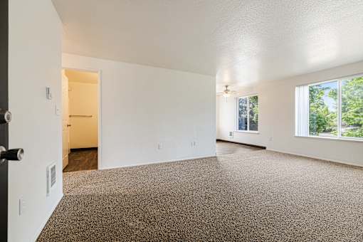A large, empty room with a carpeted floor and a doorway leading to another room.