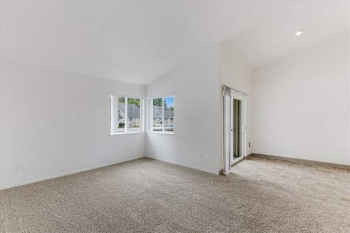 A spacious room with a carpeted floor and a door leading to another room.