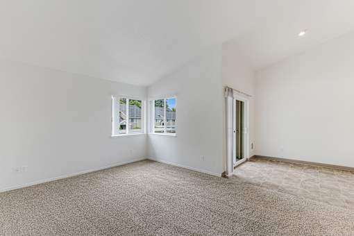 A room with a carpeted floor and a window overlooking a street.