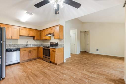 A kitchen with wooden cabinets and a black fan.