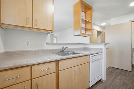 A kitchen with wooden cabinets and a white dishwasher.