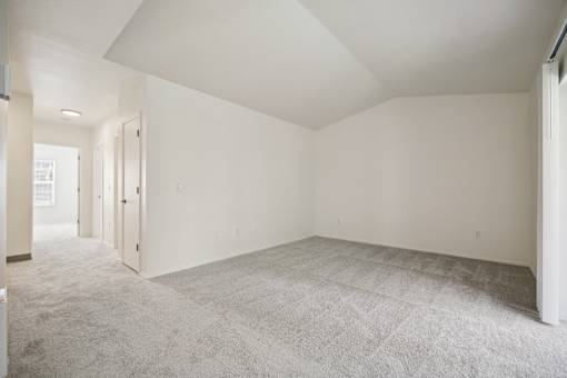 A large empty room with carpeted floor and white walls.
