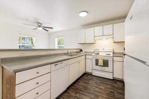 A kitchen with white cabinets and a wood floor.