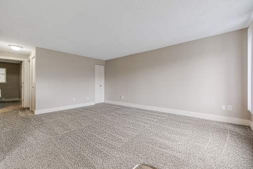 A large, empty room with carpeted flooring and white walls.