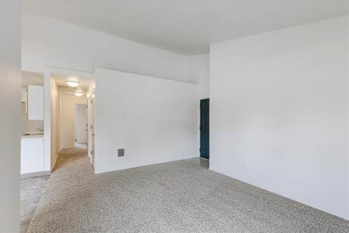 A large empty room with a carpeted floor and white walls.