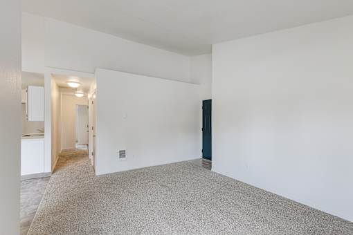 A large empty room with a carpeted floor and white walls.