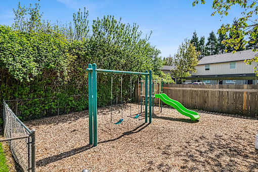 A playground with a green slide and a green monkey bars.