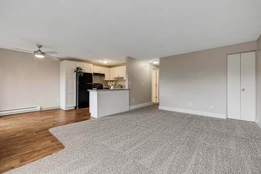 A spacious living room with a kitchen area in the background.
