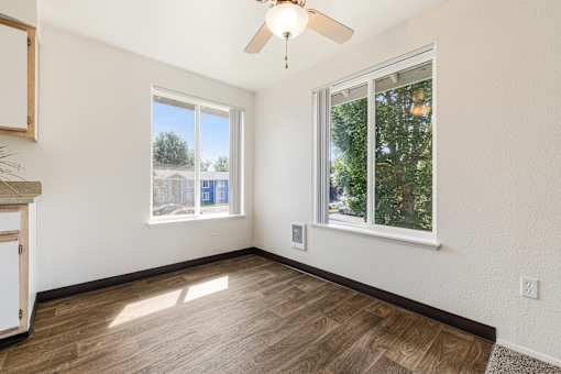 A room with a ceiling fan and two windows.