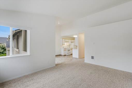 A spacious, empty room with a window and a door leading to another room.