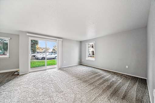 A room with a carpeted floor and a window overlooking a parking lot.