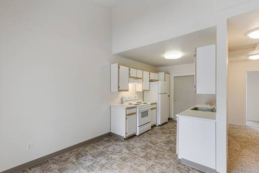 A kitchen with white appliances and a tiled floor.