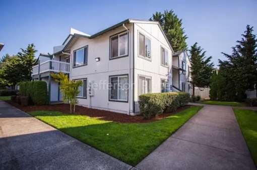 A white two-story house with a driveway in front.