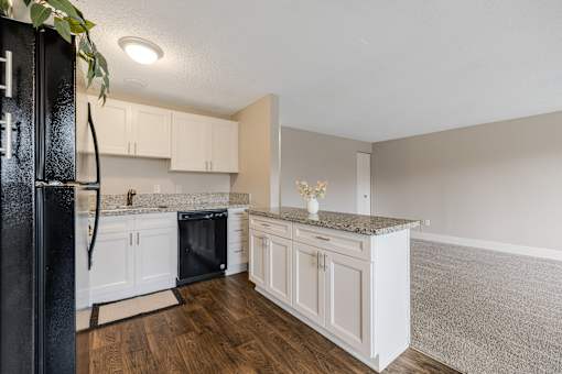 A kitchen with white cabinets and a black fridge.