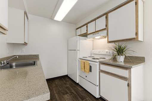A kitchen with white appliances and wooden cabinets.