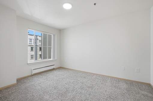 A room with a window and a carpeted floor.