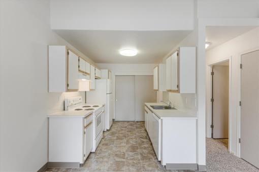 A kitchen with white appliances and cabinets.