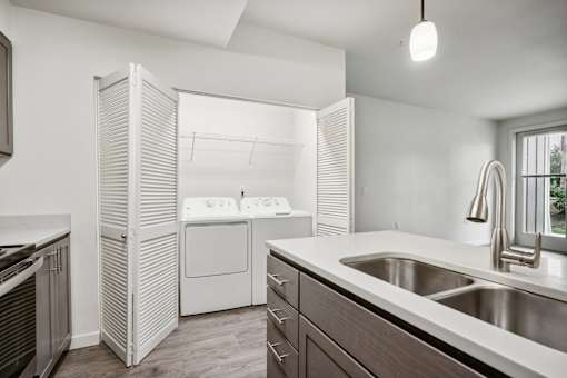 A modern kitchen with a stainless steel sink and white appliances.