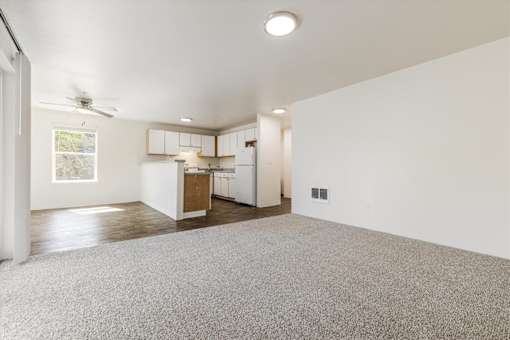 A spacious room with a carpeted floor and a ceiling fan.