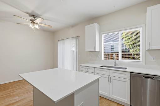 A kitchen with a white countertop and a ceiling fan.