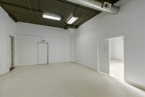 A white room with a door on the left and an exit sign on the wall.