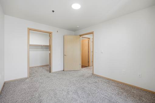 A room with two open doors and a carpeted floor.