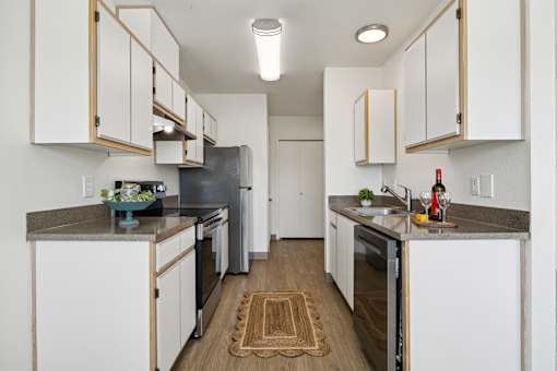 A kitchen with white cabinets and a grey counter top.
