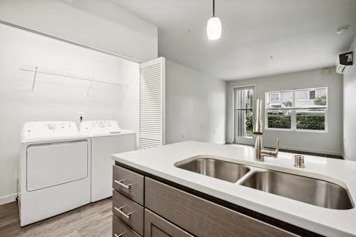 A modern kitchen with a white washing machine and a stainless steel sink.