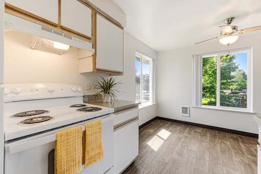 A kitchen with a white stove and wooden cabinets.