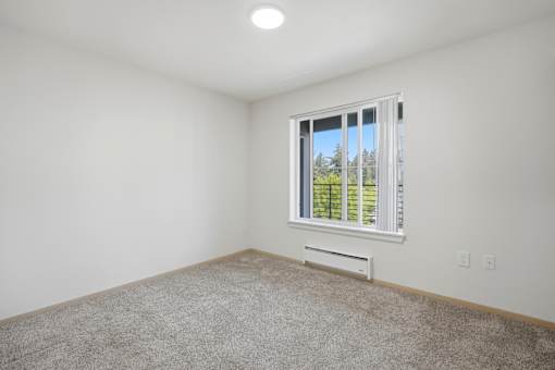 A room with a window and a white air vent.