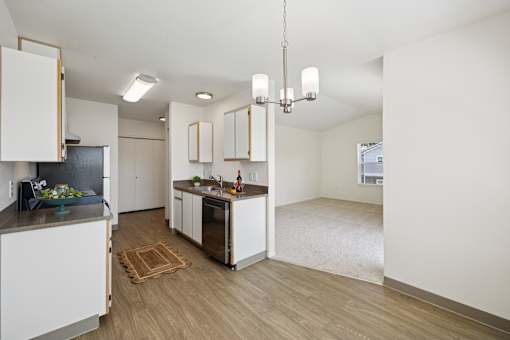 A kitchen with white cabinets and a wooden floor.