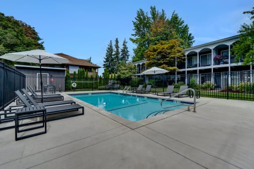 a swimming pool with lounge chairs and umbrellas in front of a building Sunset Station Apartments Portland Oregon 